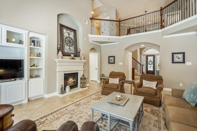 4611 Kings Landing Ln, Katy, TX 77494 - living room with a high ceiling, arched walkways, a glass covered fireplace, baseboards, and tile patterned flooring