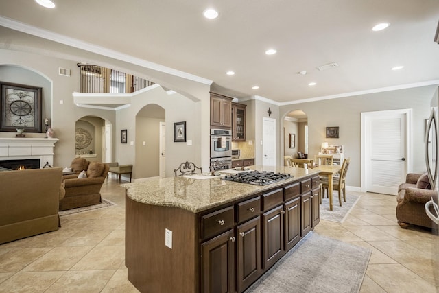 4611 Kings Landing Ln, Katy, TX 77494 - kitchen featuring arched walkways, light tile patterned flooring, crown molding, stainless steel appliances, and a kitchen island