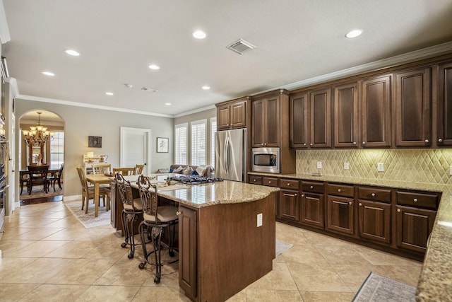 4611 Kings Landing Ln, Katy, TX 77494 - kitchen featuring appliances with stainless steel finishes, a center island, arched walkways, a breakfast bar, and ornamental molding