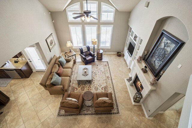 4611 Kings Landing Ln, Katy, TX 77494 - living area featuring a warm lit fireplace, a high ceiling, ceiling fan, tile patterned flooring, and baseboards