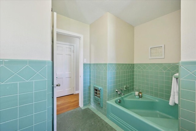 1175 N 23rd St, Beaumont, TX 77706 - full bathroom featuring heating unit, a garden tub, tile walls, wainscoting, and tile patterned floors