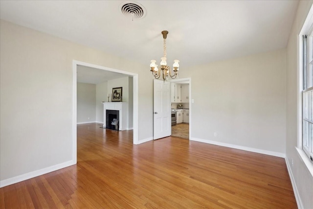 1175 N 23rd St, Beaumont, TX 77706 - unfurnished dining area featuring a chandelier, light wood-type flooring, baseboards, and a fireplace with flush hearth