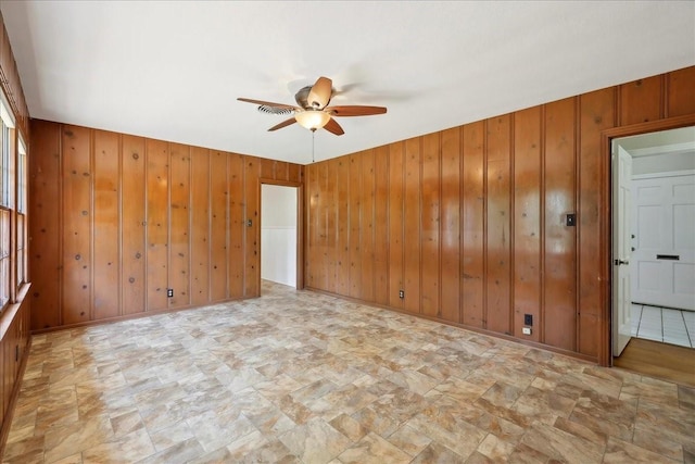 1175 N 23rd St, Beaumont, TX 77706 - spare room with ceiling fan, wooden walls, and stone finish flooring