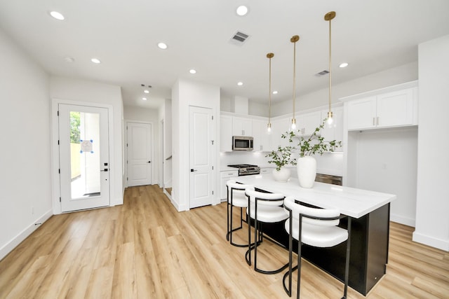 4602 Bristol St, Houston, TX 77009 - kitchen featuring stainless steel appliances, white cabinets, a center island, recessed lighting, and light wood-style floors