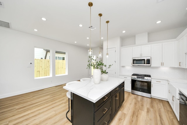 4602 Bristol St, Houston, TX 77009 - kitchen featuring appliances with stainless steel finishes, white cabinetry, a kitchen island, decorative backsplash, and recessed lighting