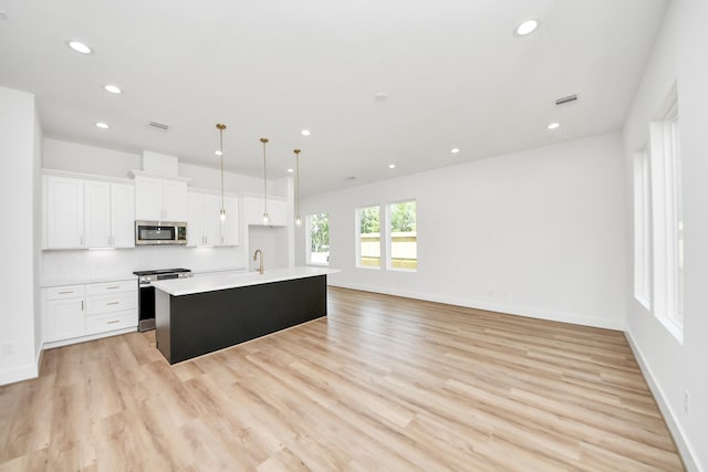 103 Frawley St, Houston, TX 77009 - kitchen featuring appliances with stainless steel finishes, an island with sink, white cabinets, light countertops, and recessed lighting