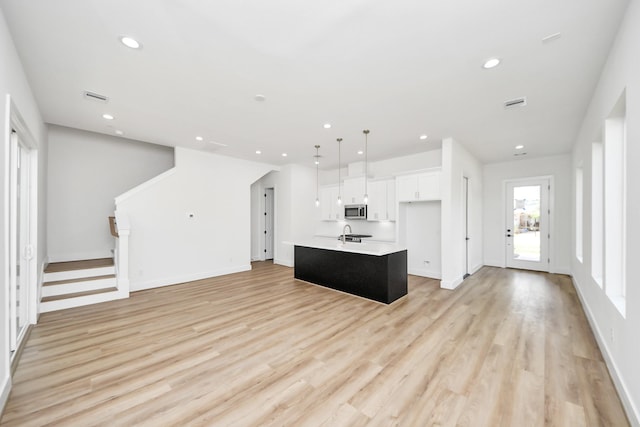 103 Frawley St, Houston, TX 77009 - kitchen with stainless steel microwave, white cabinetry, a center island with sink, light countertops, and recessed lighting
