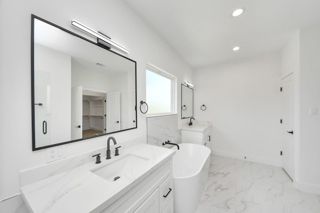 103 Frawley St, Houston, TX 77009 - full bath with two vanities, marble look tiles, a freestanding tub, recessed lighting, and baseboards