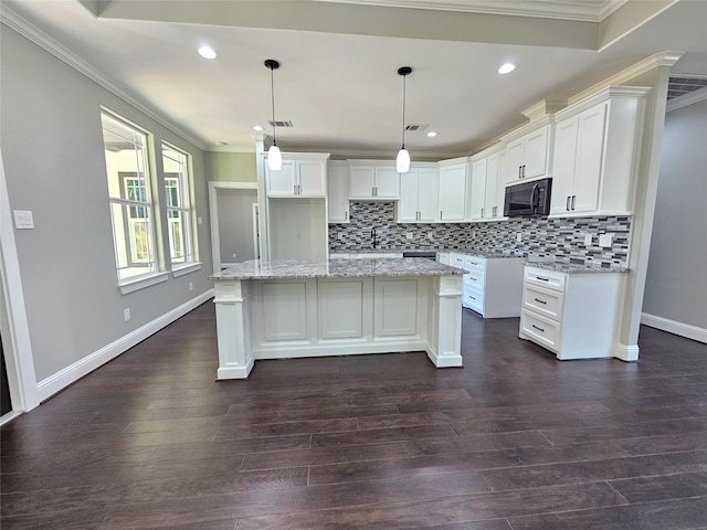 4319 Trail Lake Dr, Houston, TX 77045 - kitchen featuring black microwave, crown molding, tasteful backsplash, a center island, and white cabinetry