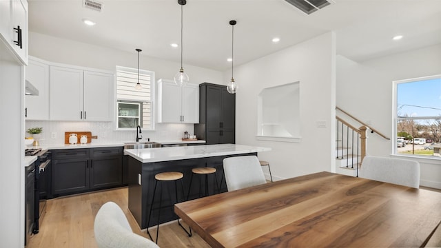 723 Marcella St Unit B, Houston, TX 77091 - kitchen featuring tasteful backsplash, a kitchen island, a sink, light wood-style floors, and white cabinets