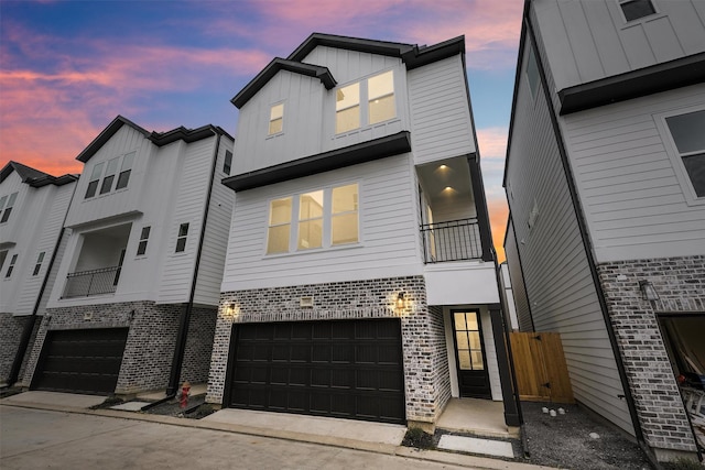 723 Marcella St Unit B, Houston, TX 77091 - view of front of home featuring board and batten siding, a garage, driveway, brick siding, and a balcony