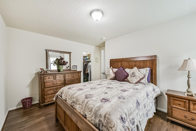 4223 Leafy Bough Ct, Humble, TX 77346 - bedroom featuring dark wood-style floors, a walk in closet, a closet, baseboards, and a textured ceiling