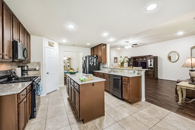 4223 Leafy Bough Ct, Humble, TX 77346 - kitchen featuring black gas range, dishwasher, freestanding refrigerator, a sink, and a peninsula