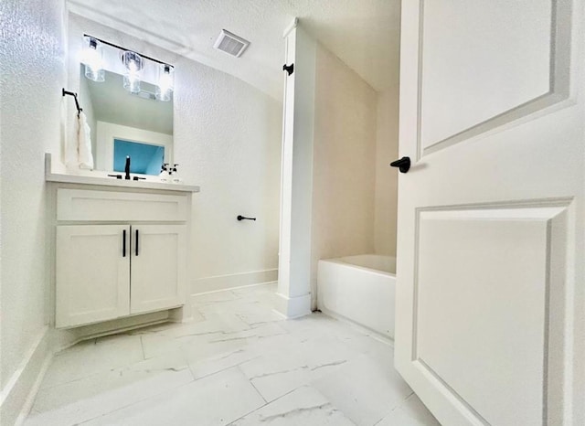 319 Wisteria St, Lake Jackson, TX 77566 - full bathroom featuring marble look tile flooring, vanity, a tub, baseboards, and a textured wall