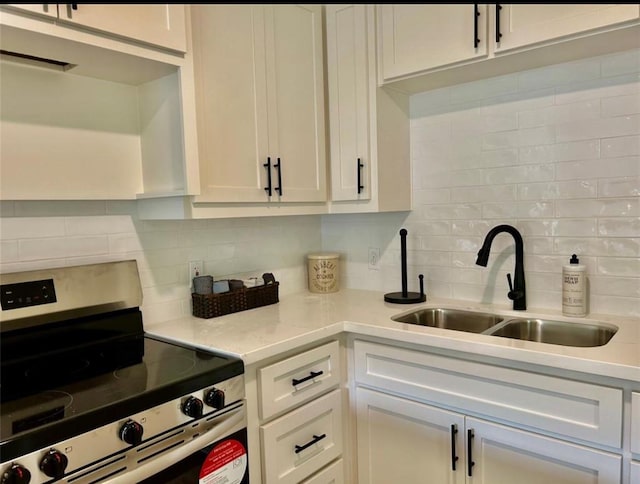 319 Wisteria St, Lake Jackson, TX 77566 - kitchen with stainless steel range with electric stovetop, a sink, backsplash, and white cabinetry