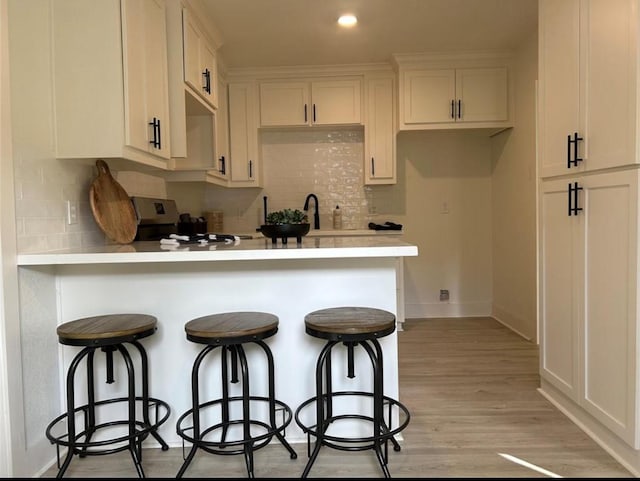 319 Wisteria St, Lake Jackson, TX 77566 - kitchen with range, a peninsula, light countertops, tasteful backsplash, and a breakfast bar area