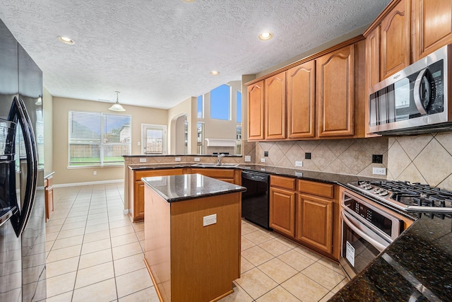13707 Kingston River Ln, Houston, TX 77044 - kitchen with appliances with stainless steel finishes, a peninsula, backsplash, dark stone countertops, and a textured ceiling
