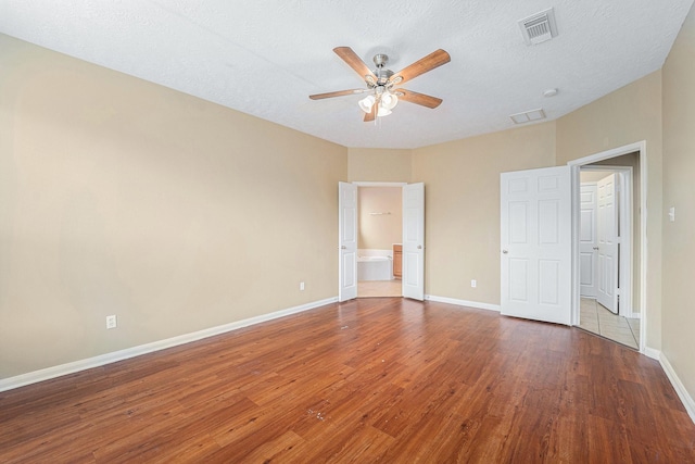 13707 Kingston River Ln, Houston, TX 77044 - unfurnished bedroom with wood finished floors, baseboards, connected bathroom, a ceiling fan, and a textured ceiling