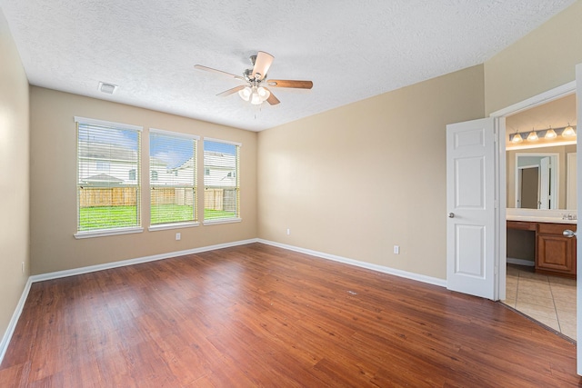 13707 Kingston River Ln, Houston, TX 77044 - unfurnished bedroom with wood finished floors, baseboards, a textured ceiling, ensuite bath, and ceiling fan