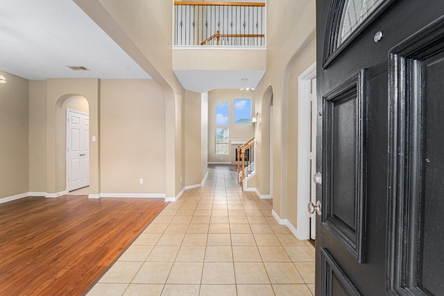 13707 Kingston River Ln, Houston, TX 77044 - entrance foyer with arched walkways, stairs, baseboards, and light wood-style floors