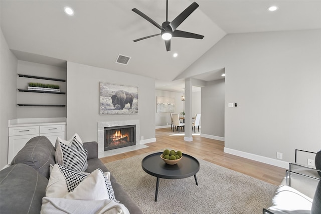 2829 Timmons Ln Unit 222, Houston, TX 77027 - living area featuring a ceiling fan, light wood-style flooring, lofted ceiling, a fireplace with flush hearth, and baseboards