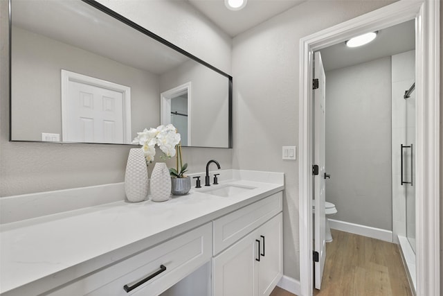 2829 Timmons Ln Unit 222, Houston, TX 77027 - bathroom with vanity, toilet, wood finished floors, baseboards, and a shower with door