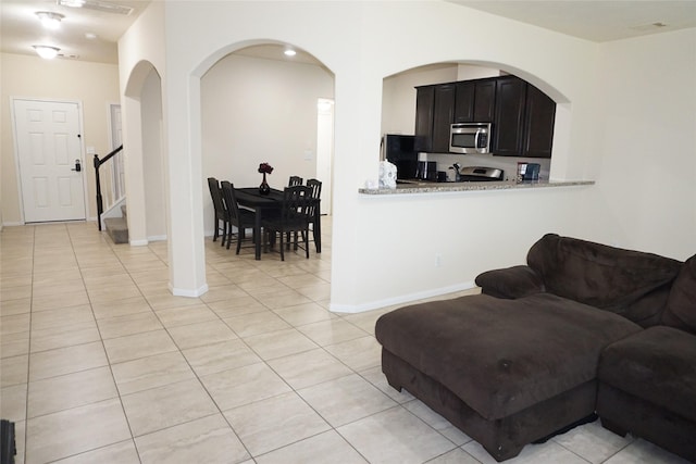 1608 Grable Cove Ln, Spring, TX 77379 - living room with light tile patterned flooring, arched walkways, baseboards, and stairway