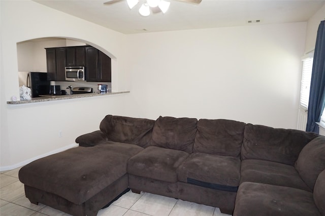 1608 Grable Cove Ln, Spring, TX 77379 - living room featuring ceiling fan, arched walkways, light tile patterned floors, and baseboards
