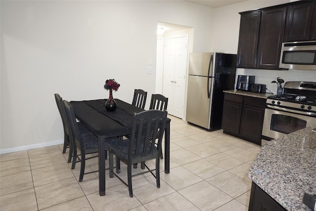 1608 Grable Cove Ln, Spring, TX 77379 - kitchen with stainless steel appliances, light stone countertops, and light tile patterned floors