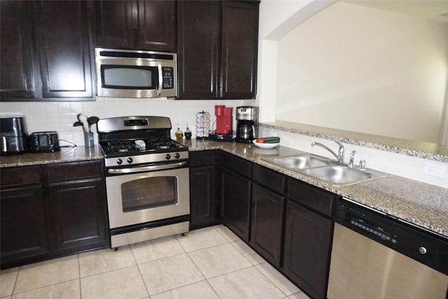 1608 Grable Cove Ln, Spring, TX 77379 - kitchen featuring stainless steel appliances, a sink, stone countertops, light tile patterned floors, and decorative backsplash