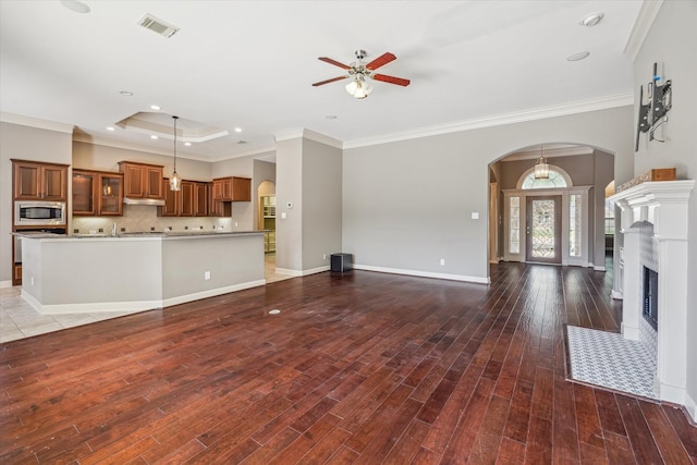 2703 Kestrel Trace Ln, Katy, TX 77494 - unfurnished living room featuring arched walkways, a ceiling fan, wood finished floors, crown molding, and baseboards