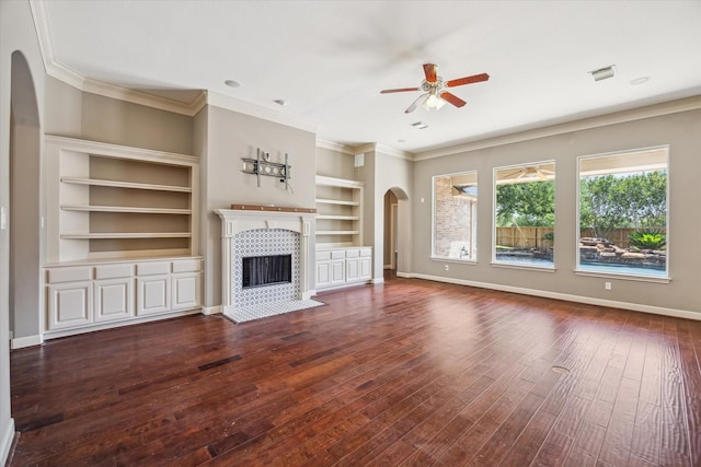 2703 Kestrel Trace Ln, Katy, TX 77494 - unfurnished living room featuring arched walkways, ceiling fan, a tiled fireplace, wood-type flooring, and built in shelves