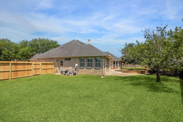2703 Kestrel Trace Ln, Katy, TX 77494 - rear view of house featuring a chimney, a patio, brick siding, an outdoor fire pit, and a shingled roof