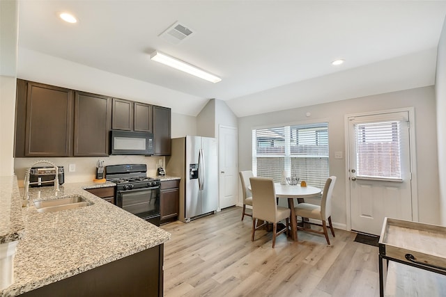 23607 Buttress Root Dr, Spring, TX 77373 - kitchen with black appliances, dark brown cabinetry, a sink, vaulted ceiling, and light wood finished floors