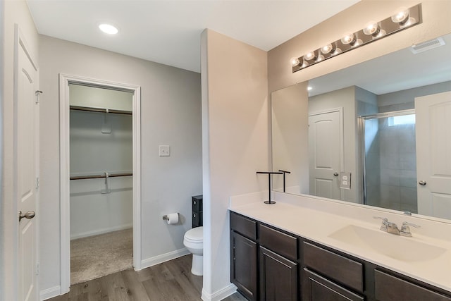 23607 Buttress Root Dr, Spring, TX 77373 - bathroom featuring wood finished floors, toilet, vanity, a spacious closet, and a shower with shower door
