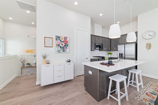 6307 Chelsea Falls Ln, Houston, TX 77008 - kitchen featuring appliances with stainless steel finishes, dark brown cabinetry, light countertops, a sink, and a kitchen bar