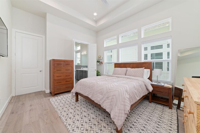 6307 Chelsea Falls Ln, Houston, TX 77008 - bedroom featuring light wood finished floors, baseboards, a towering ceiling, ensuite bath, and a raised ceiling