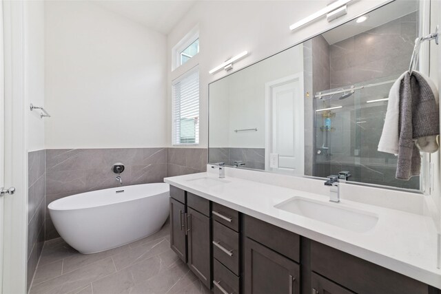 6307 Chelsea Falls Ln, Houston, TX 77008 - bathroom featuring double vanity, a stall shower, a freestanding tub, marble look tiles, and a wainscoted wall
