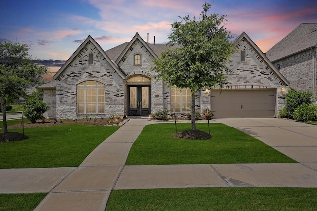 13303 Itasca Pine Dr, Humble, TX 77346 - french country style house with french doors, concrete driveway, a yard, a garage, and brick siding