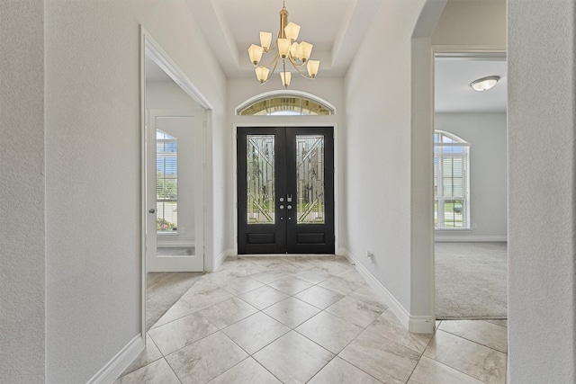 13303 Itasca Pine Dr, Humble, TX 77346 - entryway featuring a chandelier, arched walkways, baseboards, a tray ceiling, and french doors