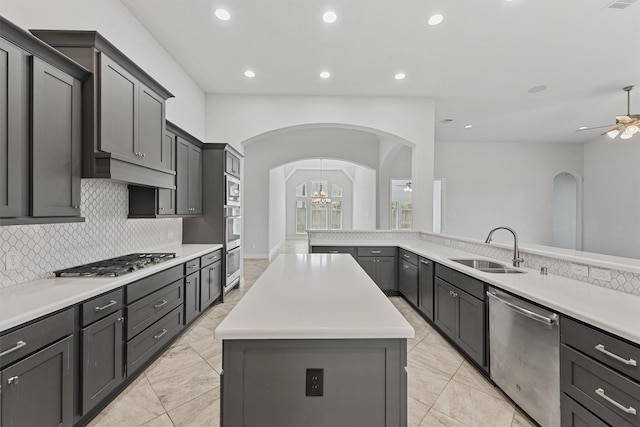 13303 Itasca Pine Dr, Humble, TX 77346 - kitchen with appliances with stainless steel finishes, a ceiling fan, a sink, arched walkways, and a center island