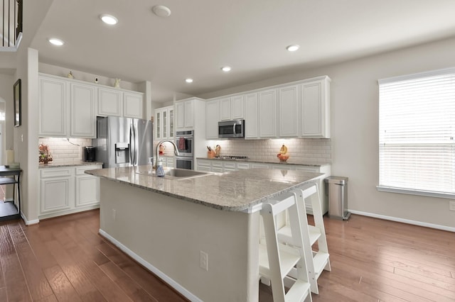 5015 Gold Lantana Trl, Spring, TX 77389 - kitchen with stainless steel appliances, backsplash, dark wood finished floors, a kitchen island with sink, and white cabinets