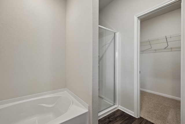 10347 Red Cardinal Dr, Cleveland, TX 77328 - full bath featuring a shower stall, a walk in closet, a garden tub, wood finished floors, and baseboards