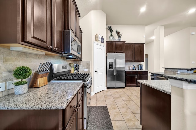 18610 Fairmont Springs Ct, Cypress, TX 77429 - kitchen with stainless steel appliances, dark brown cabinetry, backsplash, and light stone counters