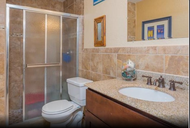 4126 Fort Bend Dr, Galveston, TX 77554 - bathroom with vanity, a stall shower, toilet, and tile walls