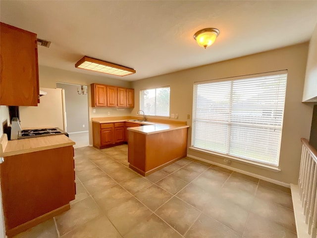 6619 Stonechase, Houston, TX 77084 - kitchen featuring a sink, range, a peninsula, light countertops, and light tile patterned floors