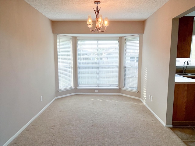 6619 Stonechase, Houston, TX 77084 - unfurnished dining area featuring carpet flooring, a textured ceiling, a chandelier, baseboards, and a sink