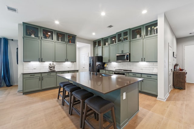 14027 Valley Creek Ct, Conroe, TX 77384 - kitchen featuring green cabinets, stainless steel microwave, refrigerator with ice dispenser, dark countertops, and recessed lighting