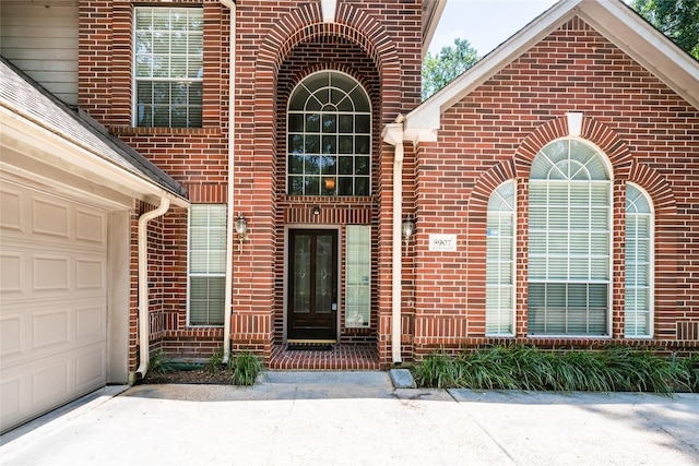 8907 Opus Ct, Houston, TX 77040 - view of exterior entry featuring brick siding, a garage, and driveway