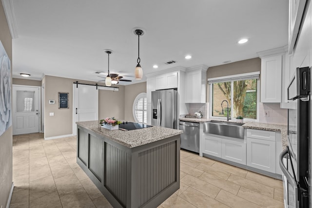 4322 Shady Springs Dr, Pasadena, TX 77586 - kitchen featuring appliances with stainless steel finishes, a barn door, a sink, ceiling fan, and decorative backsplash